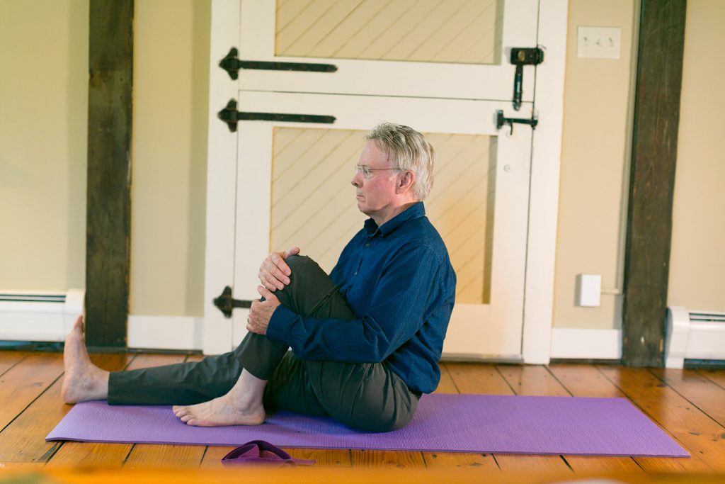 man on yoga mat preparing to do gentle yoga seated twist